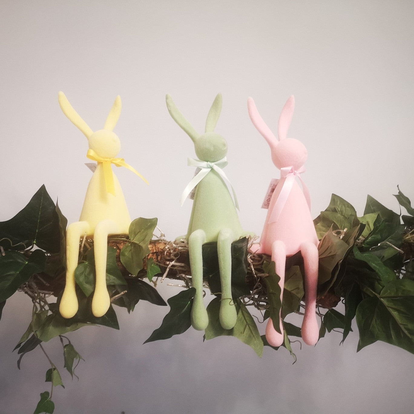 Kantenhocker Hase in Rosa, Gelb und Grün auf einem Ast